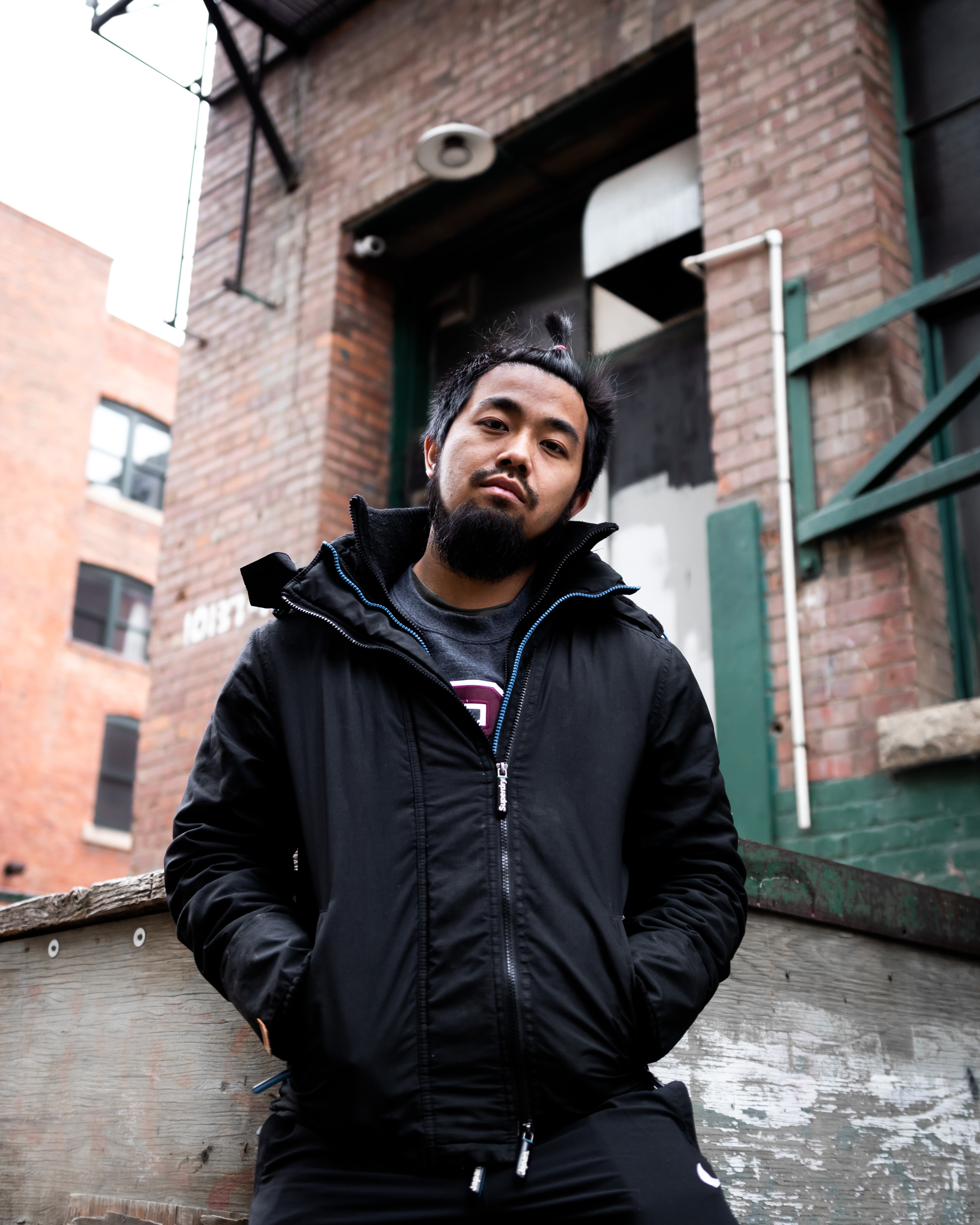 Asian man poses for the camera against an urban background